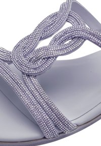 Purple sandal featuring braided straps adorned with small clear gemstones, open toe design, and a smooth, matte sole.