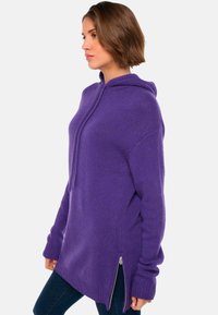 Lila Kapuzenpullover mit entspannter Passform, strukturiertem Strick, Kängurutasche und seitlichen Reißverschlüssen. Verfügt über eine verstellbare Kapuze und gerippte Bündchen.