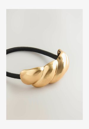 Chouchou doré avec trois accents métalliques courbés et brillants, et un bandeau élastique noir, présentant une texture lisse et un design sans couture.