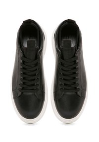 Sneaker in pelle nera con una texture liscia, punta tonda, lacci tono su tono e suola in gomma bianca, dotate di un ciclo sulla parte posteriore.