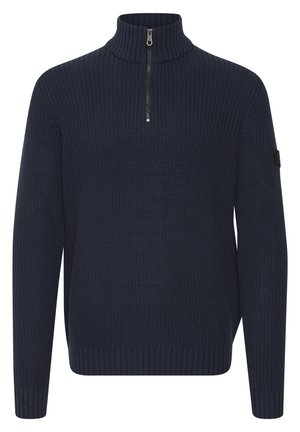 Pull en demi-zip bleu marine avec texture côtelée et longues manches. Présente un col haut et un petit patch logo noir sur la manche.