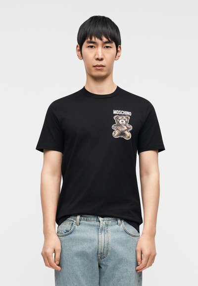 Μαύρο βαμβακερό T-shirt με στρογγυλή λαιμόκοψη και κοντά μανίκια, με γραφικό αρκούδας και το λογότυπο «Moschino» τυπωμένα στο στήθος.