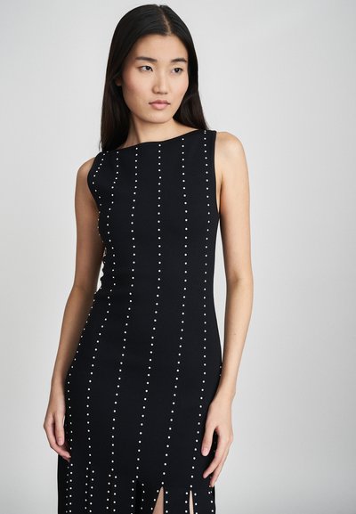 Black sleeveless dress with a fitted design, featuring vertical rows of white embellishments and slit detailing at the hem.