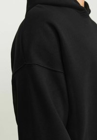 Black hoodie featuring a relaxed fit, smooth texture, and visible stitching detail along the shoulders and neckline.