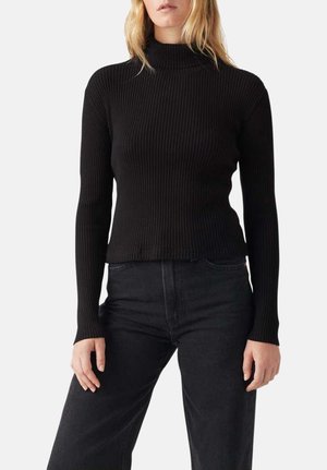 Pull turtleneck noir à côtes, à manches longues, au design ajusté et à l'ourlet court, assorti à un jean noir taille haute.