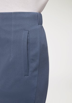 Gonna blu navy con una texture liscia, dotata di tasche laterali e di una vita piatta. Il tessuto appare leggero e leggermente strutturato.