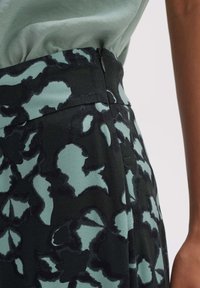 Svarta tygbyxor med ett abstract blommönster i mörkgrön och turkos. Har dragkedja och en mjuk yta vid midjan.