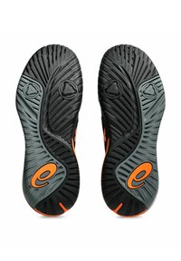 Suelas de zapatos de goma en negro y gris con un patrón texturizado, que presentan acentos naranjas y logotipos circulares, diseñadas para ofrecer agarre y durabilidad.