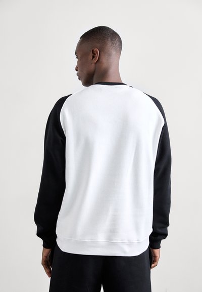 Czarno-biała bluza z raglanowymi rękawami, miękka w dotyku i z ribbowanymi mankietami. Tył jest dominująco biały.