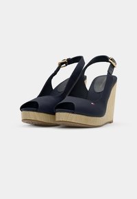 Sandalias cuña navy con punta abierta, parte superior de tela y una plataforma texturada en beige. Correa ajustable con un hebilla en tono dorado para un ajuste seguro.