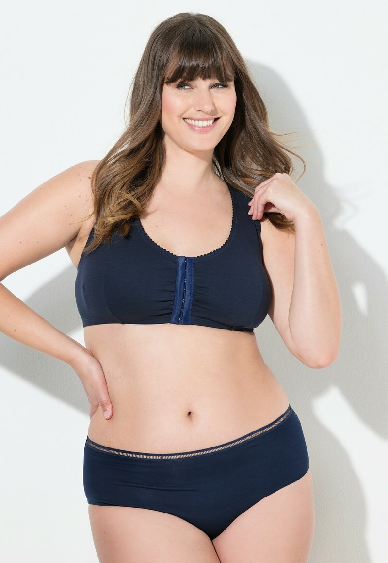 Tmavě modrá podprsenka z měkké látky s kulatým výstřihem a zapínáním vpředu. Ladící tmavě modré kalhotky s jemným elastickým akcentem v pase.