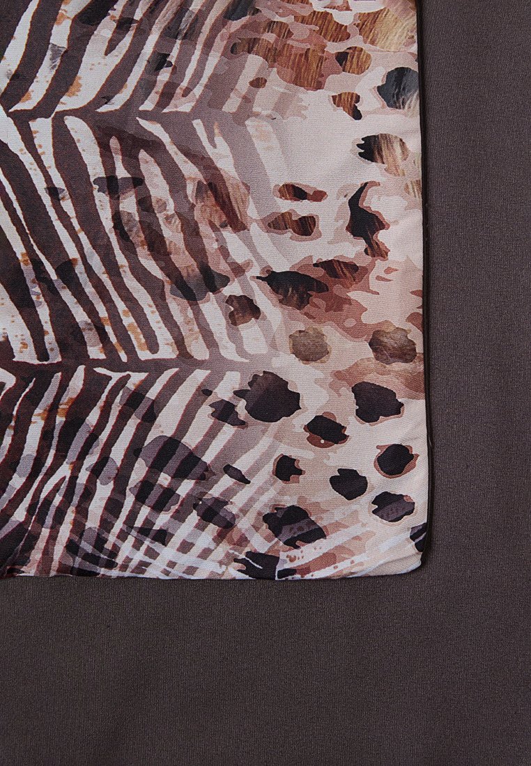 Tela impresa con patrones de animales abstractos en tonos marrones, negros y crema. Textura suave por un lado, en contraste con una tela sólida oscura.
