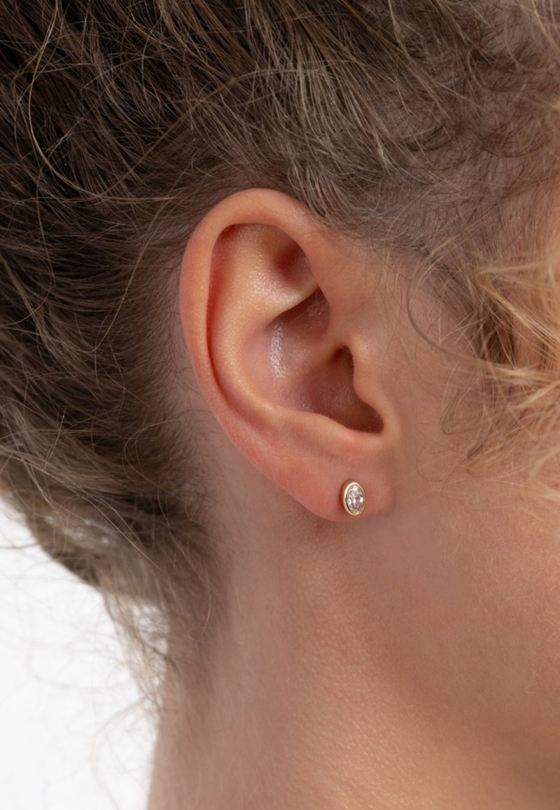 Boucles d'oreilles en or rose avec une pierre précieuse claire en forme d'oval, sertie dans un chaton minimaliste. Texture lisse, design petit et discret.