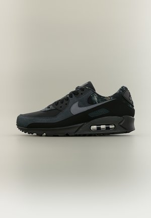 Czarny i ciemnoszary sneaker Nike Air Max z widoczną poduszką powietrzną i teksturowanymi detalami z tkaniny na neutralnym tle.