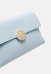 Světle modrá kožená kabelka s kulatým uzávěrem v zlatém tónu, hladkým povrchem a čistým obdélníkovým designem.