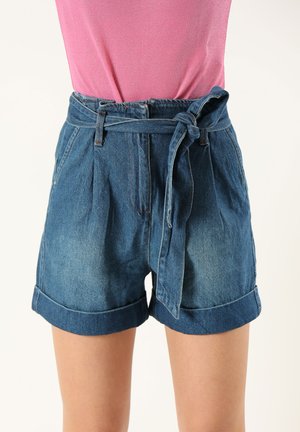 Shorts en denim taille haute, avec une ceinture nouée, un devant plissé et des ourlets retroussés. Le tissu est d'un bleu moyen avec un léger dégradé.