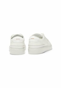 Sneakers bianchi in pelle con tomaie testurizzate, accenti a contrasto e una soletta spessa bianca. Caratterizzano un design minimalista e un dettaglio del logo sul lato.