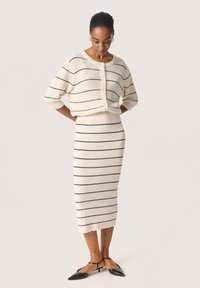 Set de îmbrăcăminte de lounge din tricot crem cu dungi orizontale negre. Pulover scurt, cu guler rotund și închidere cu nasture; fustă ajustată, de lungime medie.