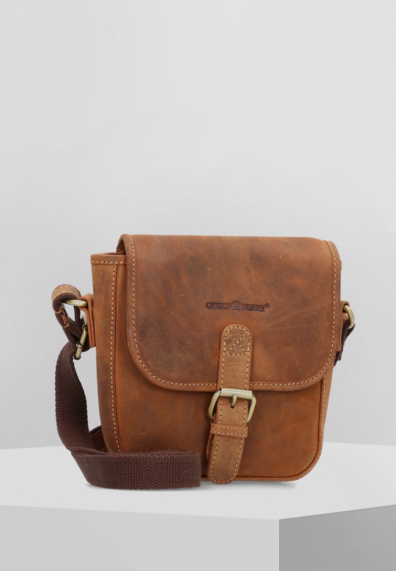 Borsa a tracolla in pelle marrone con un pattino a cerniera, dettagli cuciti, una fibbia in metallo e una tracolla in tela. Presenta un logo sul davanti.