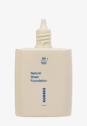 Fond de teint naturel KORRES dans un contenant carré, blanc cassé avec du texte bleu ; il possède un capuchon à vis avec un embout pour le dosage.