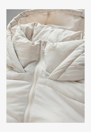 Jasno beżowa kurtka puchowa z wysokim kołnierzem, z centralnym zamkiem błyskawicznym i miękkim, teksturowanym materiałem. Pikowana konstrukcja z widocznymi szwami.