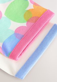 Tessuto di cotone colorato con grandi cuori sovrapposti in rosa, verde, arancione e blu, con polsini a costine rosa e blu.