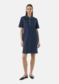 Jeanshemdkleid in Dunkelblau, mit kurzen Ärmeln, zwei Brusttaschen, einer Knopfleiste und einer geraden Silhouette, abgeschlossen mit einem Saum.