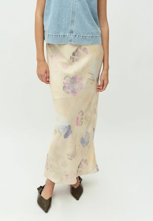 Floral satijnen rok in crème met aquarel-stijl paarse en groene bloemen, met een vloeiende silhouette en een zijsplit, gedragen met donkerbruine hakschoenen.