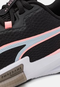 Svart sportskor med mesh-ovandel, med ljusblå och rosa accenter samt en vit sula med texturerad detalj vid hälen.