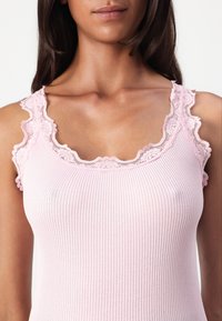 Débardeur rose à côtes avec des bordures en dentelle aux épaules et au col. Texture lisse avec un design ajusté et de délicates accents en dentelle florale.
