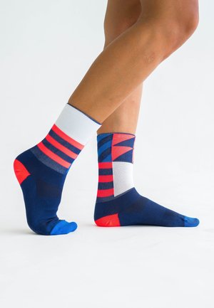 Mehrfarbige Knöchelsocken mit geometrischen Mustern in Marineblau, Rot und Weiß, einschließlich kontrastierenden Fersen- und Zehenakzenten.
