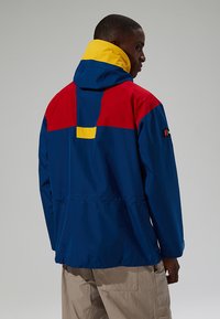 Farbblockierte Jacke mit blauer Basis, rohem oberen Abschnitt und gelber Kapuze. Aus wasserabweisendem Material in lässiger Passform gefertigt.