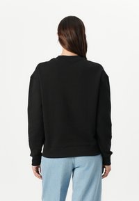 Zwarte sweatshirt met ronde hals en verlaagde schouders, gemaakt van katoen. Heeft een geribbelde zoom en manchetten, platte naden en een gladde textuur.