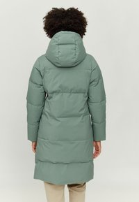 Long puffer coat in matte light green, featuring a hood, quilted sections, and long sleeves, with a straight cut to mid-thigh length.
