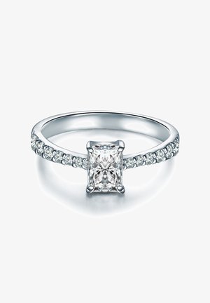 Pierścionek zaręczynowy z diamentem w białym złocie, z centralnym kamieniem w kształcie princessy oraz obrączką ozdobioną mniejszymi okrągłymi kamieniami po obu stronach.