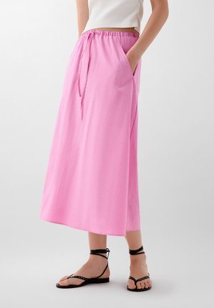 Pink midi skirt with vertical stripes, side pockets, an elastic waistband, and a drawstring tie. Worn with black strappy sandals.