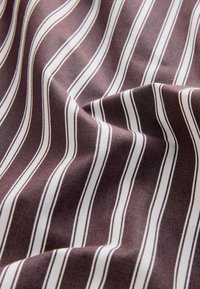 Tessuto di cotone con sfondo marrone scuro caratterizzato da strisce verticali bianche e marrone chiaro, texture liscia e sottile lucentezza.