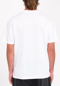 T-shirt blanc à col rond avec des manches courtes, en coton, présentant une texture lisse et une coupe décontractée. Coutures à plat et sans graphique.
