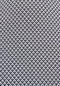 Motif géométrique en noir et blanc composé de petits triangles formant des formes de diamant sur un fond en tissu texturé.