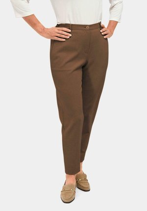 Pantalons tailleurs marron avec une texture lisse, dotés d'une fermeture à bouton à l'avant, de passants de ceinture et de poches latérales. Associés à des mocassins beiges.
