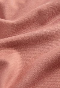 Texturovaná látka v teplé růžové barvě s jemným, lehce kartáčovaným povrchem. Viditelný tkaný vzor dodává hloubku.