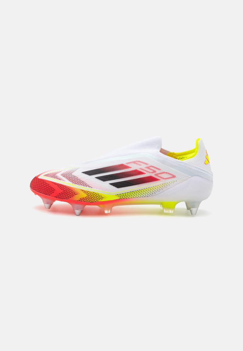 White soccer cleat with red and yellow accents, a sleek design, mesh upper, black branding, and transparent studs on the outsole.