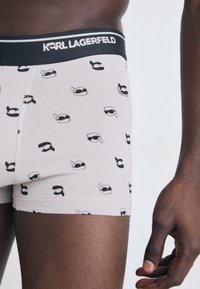 Herre boxer briefs i lys grå bomullsblanding med svart trykk av tegneseriebriller. Har en svart midjeelastikk med "KARL LAGERFELD" merket.