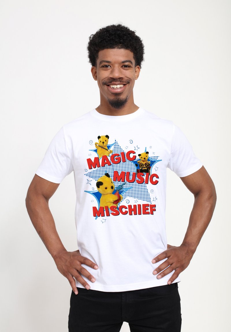 Bílý bavlněný tričko s barevnými grafickými motivy karikatury medvěda a textem "MAGIC MUSIC MISCHIEF" v červené barvě, umístěným na modrém hvězdném vzoru.