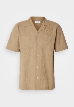 Short-sleeve, beige shirt made of textured fabric. Features a spread collar, two front pockets, and button closure in a relaxed fit.