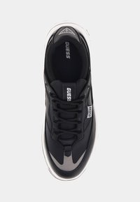 Sneaker nera con tomaia in pelle liscia, accenti grigi a contrasto e suola in gomma bianca. Presenta lacci texture e logo di marca.