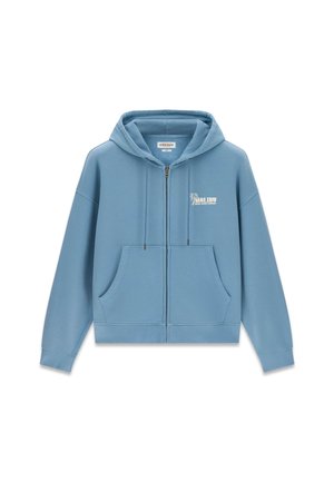 Lichtblauwe zip-up hoodie met zakken aan de voorkant en "Malibu Guess Jeans Company" logo op de linkerborst, voorzien van een capuchon met trekkoord.