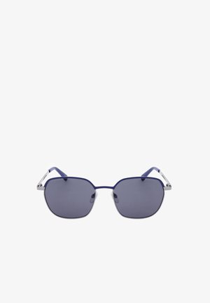 Occhiali da sole con montatura blu, lenti quadrate grigio scuro e aste argento poggiati su uno sfondo bianco.