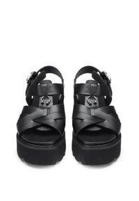 Sandali platform neri con ampie cinghie intrecciate in pelle e suola spessa. Presentano un dettaglio con fibbia e superficie texturizzata sulla parte superiore.