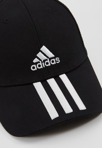 Zwarte baseballpet van stof, met een wit geborduurd logo en drie witte strepen op het voorpaneel.